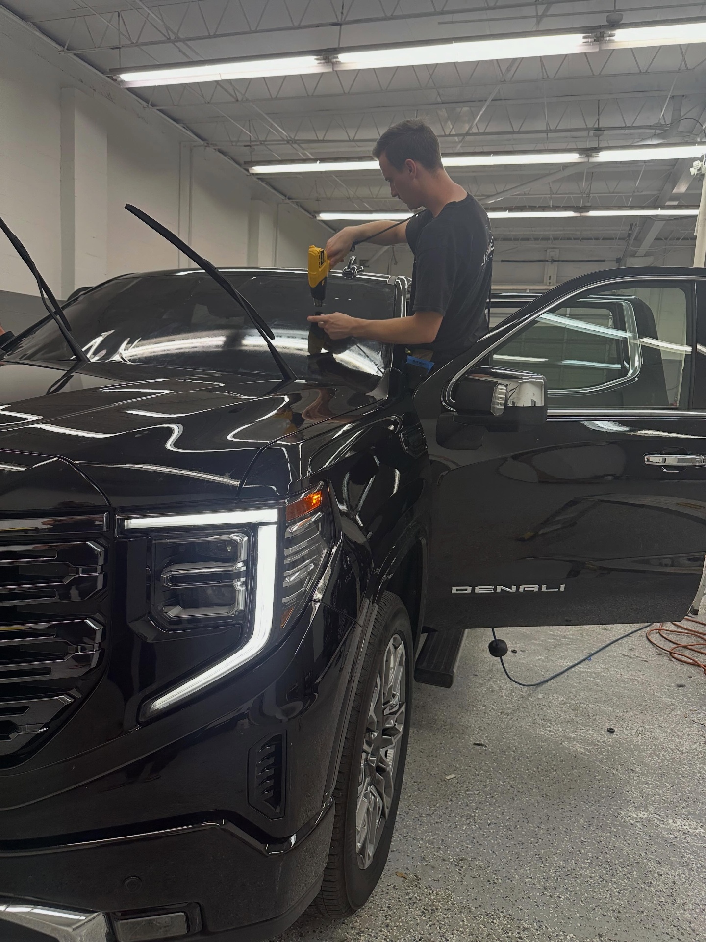 Lifetime Tint installer tinting a black GMC Denali